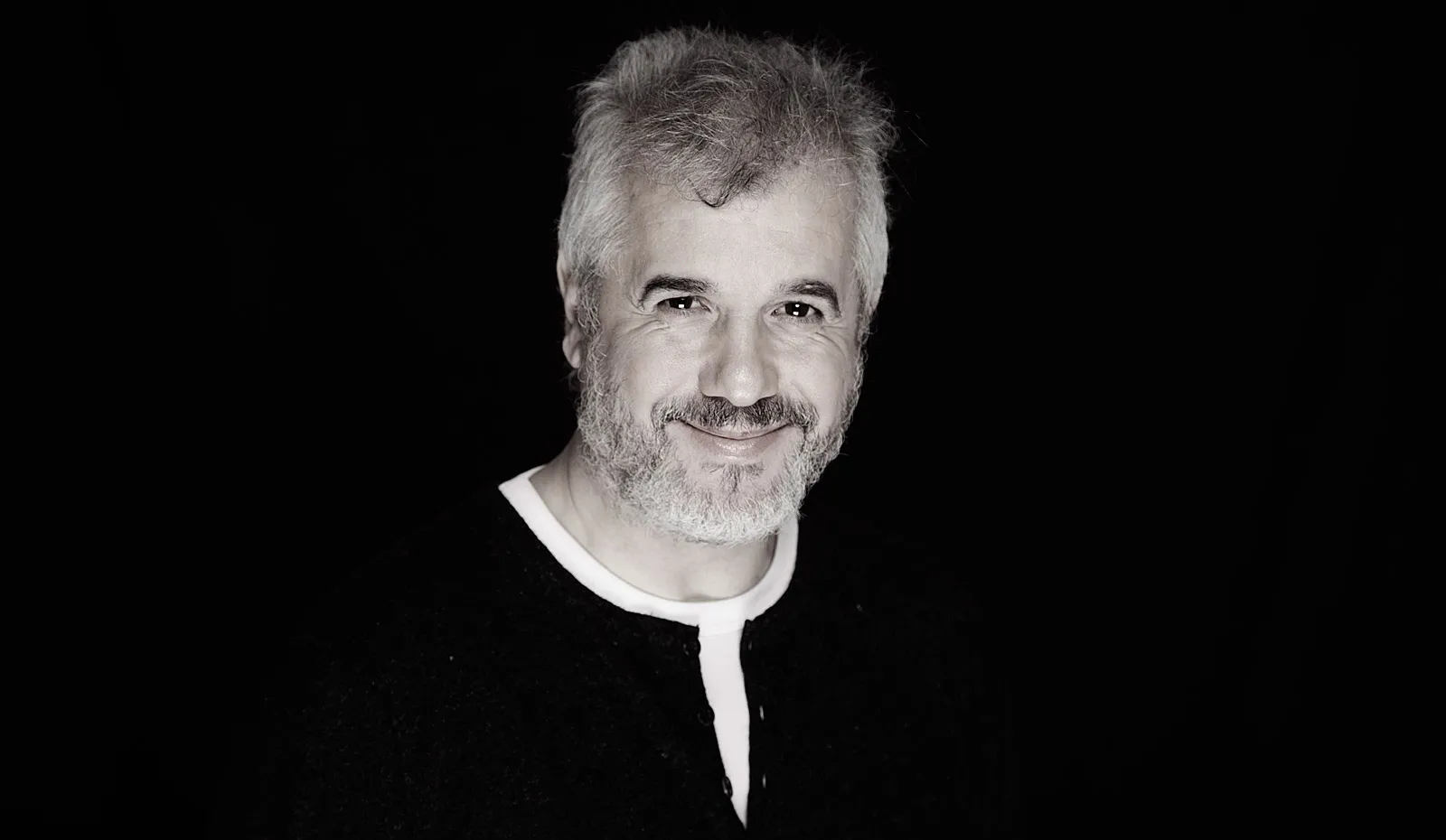 Retrato de Roberto Calvo sonriendo, sobre fondo negro
